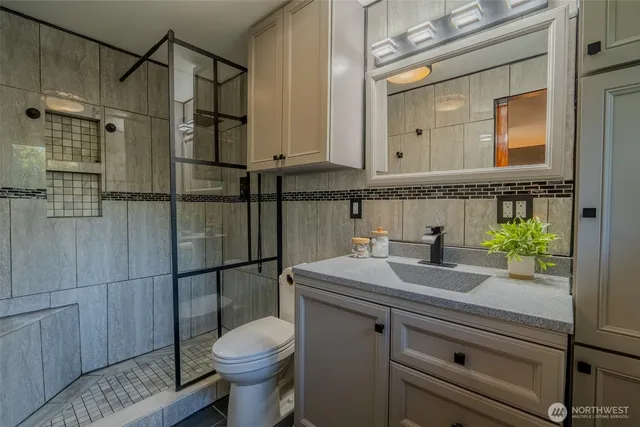 a bathroom with a granite countertop toilet sink and mirror