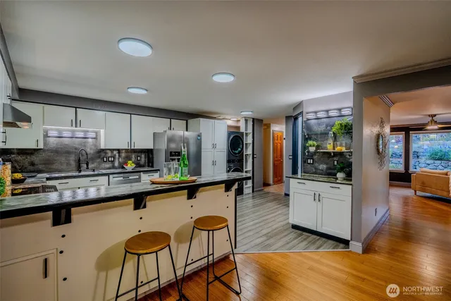 a kitchen with stainless steel appliances granite countertop a stove a sink dishwasher and a refrigerator with wooden floor