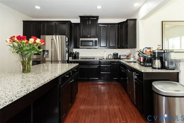 a kitchen with stainless steel appliances granite countertop a sink a stove and a wooden floors
