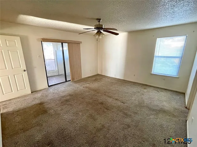 an empty room with windows and fan