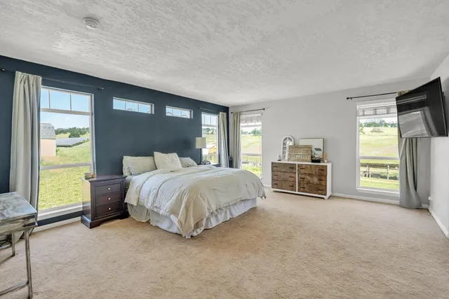 a spacious bedroom with a bed and a flat screen tv