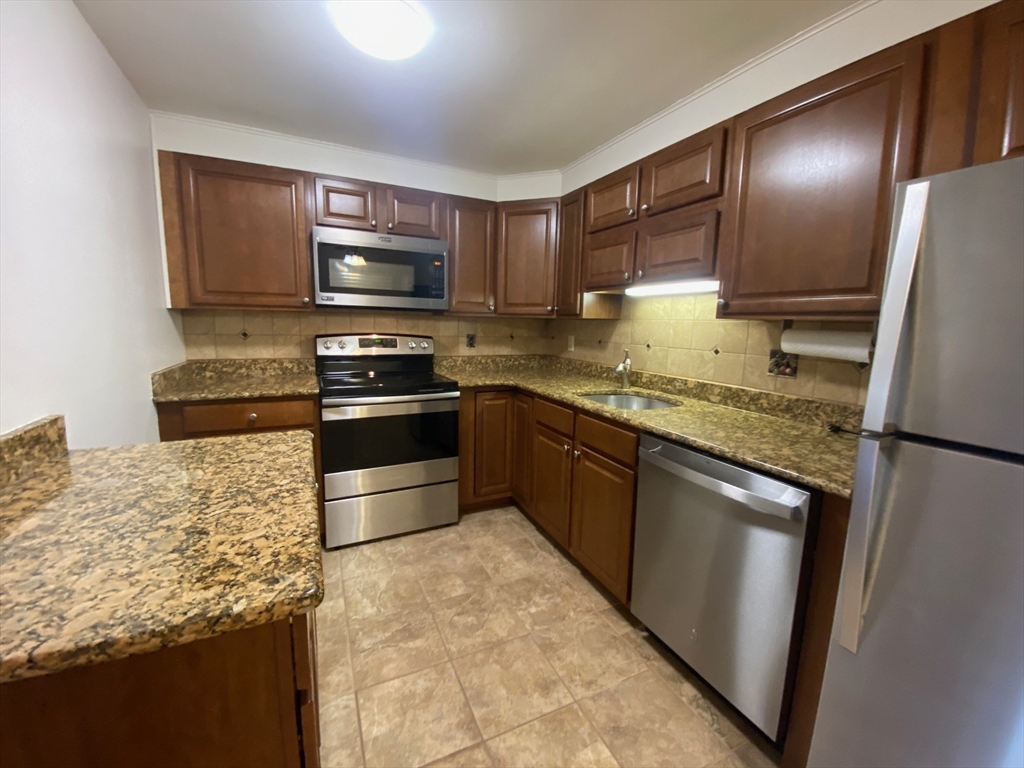 8 Old Colony Lane, Unit 2 Arlington, MA 02476 - Photo 11 of 12 a kitchen with kitchen island granite countertop a stove microwave and refrigerator