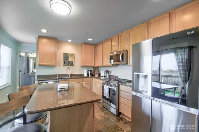 a kitchen with stainless steel appliances granite countertop a sink refrigerator stove and microwave