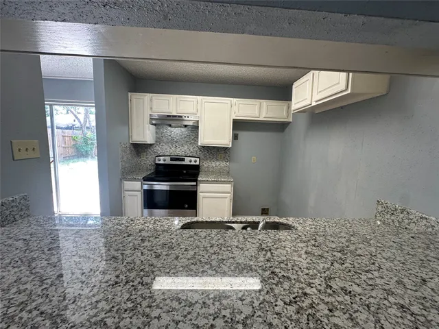 a kitchen with granite countertop a stove and a refrigerator