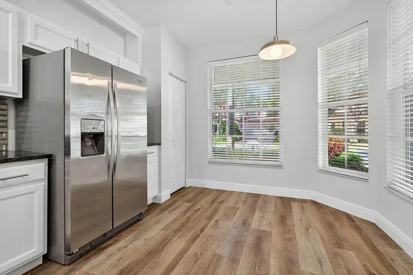 a view of a kitchen with wooden floor a ceiling fan and windows