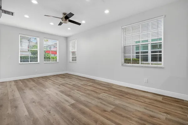 an empty room with wooden floor and windows