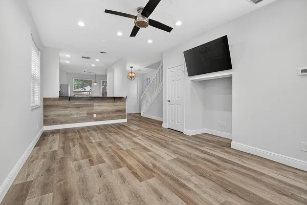 a view of kitchen and empty room with wooden floor