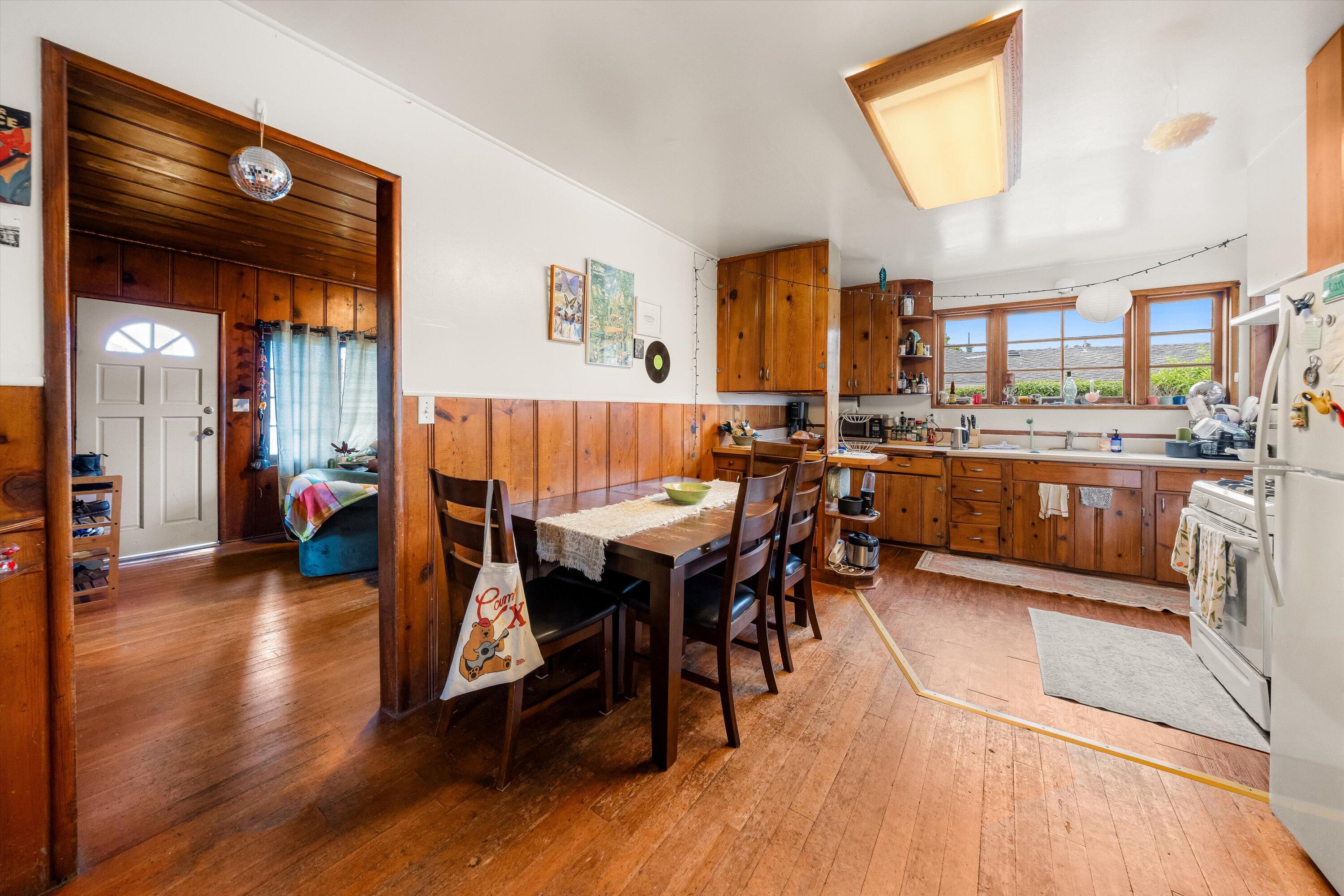 6670 Sueno Road Isla Vista, CA 93117 - Photo 6 of 20 a dining room with wooden floor a chandelier a glass table and chairs