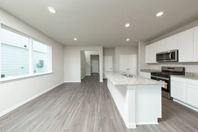 a large kitchen with stainless steel appliances granite countertop a lot of counter space and wooden floor