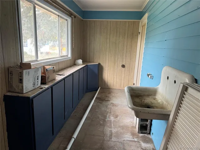 a hallway with a chair and white cabinet with wooden floor