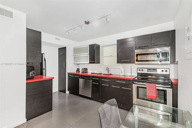 a kitchen with stainless steel appliances kitchen island granite countertop a refrigerator and a stove top oven