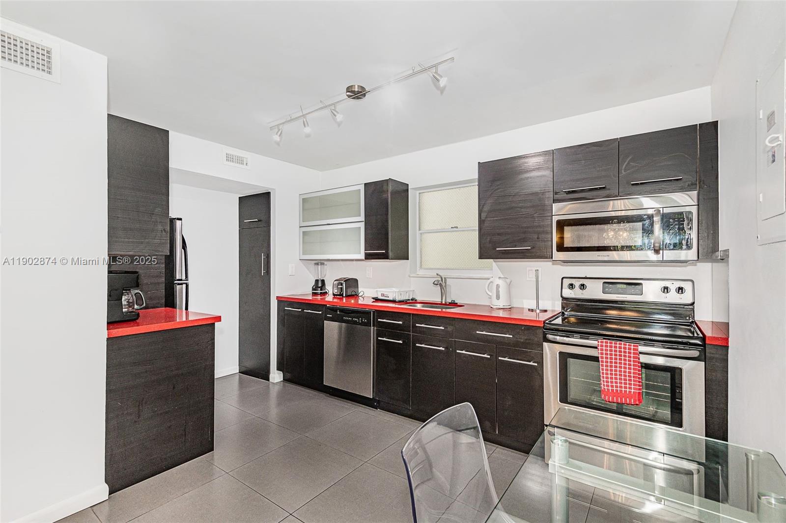 201 178th Drive, Unit 212 Sunny Isles Beach, FL 33160 - Photo 3 of 15 a kitchen with stainless steel appliances kitchen island granite countertop a refrigerator and a stove top oven