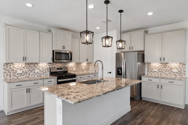 a kitchen with kitchen island granite countertop a sink appliances cabinets and counter space
