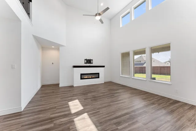 a view of empty room with wooden floor and fan