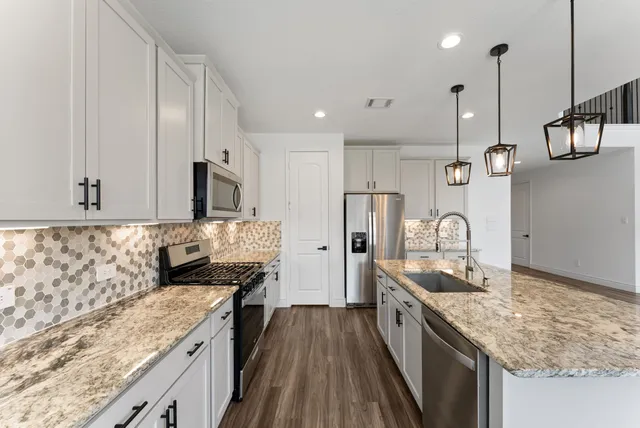 a kitchen with stainless steel appliances granite countertop a sink a stove and a wooden floors