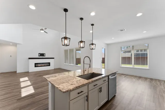 a kitchen with stainless steel appliances granite countertop a sink a oven a stove and a wooden floors