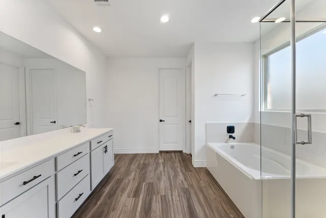 a spacious bathroom with a tub sink and mirror