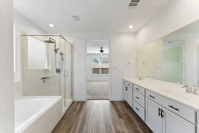 a bathroom with a tub sink shower and two mirror