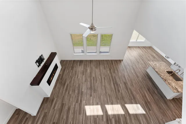 a view of an empty room with wooden floor and windows