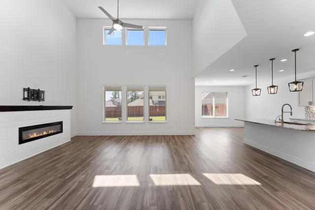 an empty room with wooden floor fireplace and windows