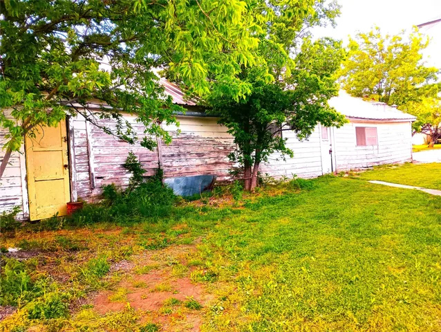 a backyard of a house with plants and large trees