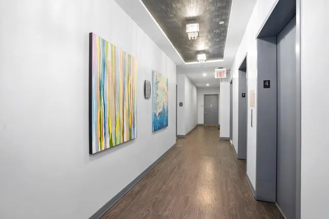 a view of a hallway with wooden floor and a bathroom