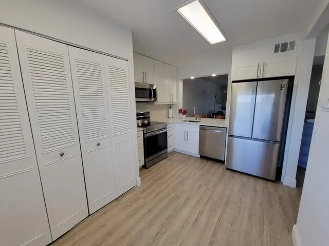 a kitchen with stainless steel appliances a refrigerator and wooden floor