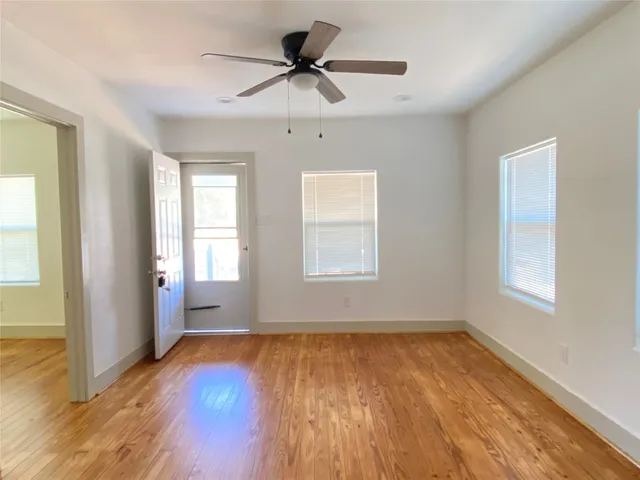 a view of empty room with wooden floor and fan