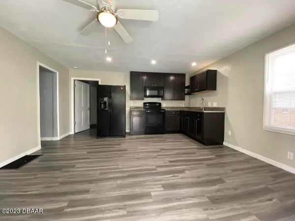 a view of kitchen with stainless steel appliances granite countertop a refrigerator a stove top oven a sink dishwasher and wooden floor