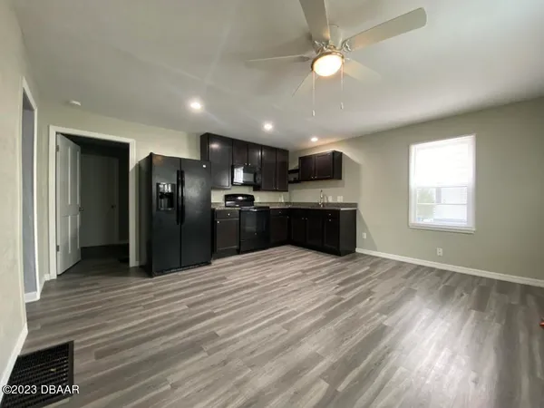 a kitchen with stainless steel appliances kitchen island granite countertop a refrigerator a stove and a wooden floors