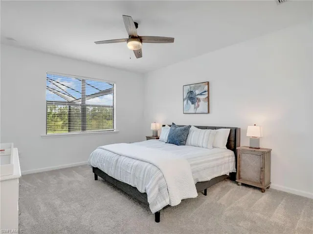 a bedroom with a bed lamp and a large window