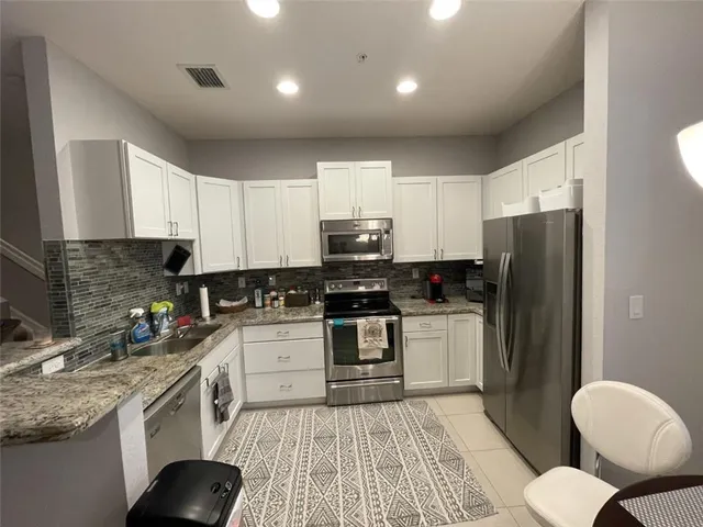 a kitchen with a sink stainless steel appliances and white cabinets