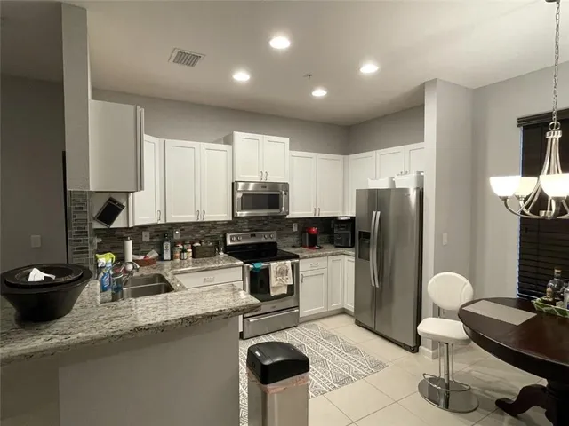 a kitchen with stainless steel appliances kitchen island granite countertop a sink refrigerator and cabinets