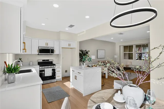 a kitchen with stainless steel appliances granite countertop a stove a sink a dining table and chairs