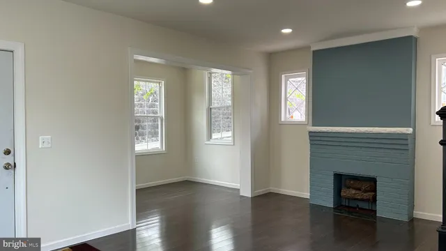 an empty room with wooden floor a fireplace and windows