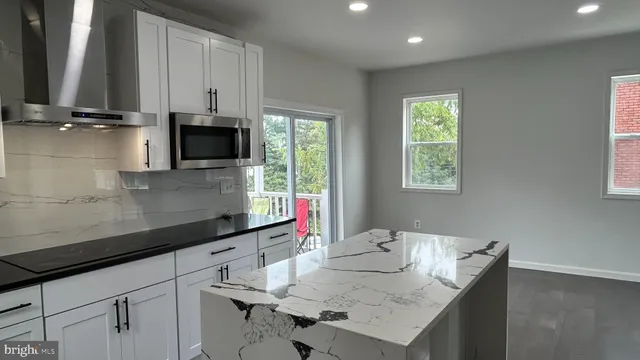 a kitchen with stainless steel appliances a sink a microwave a stove and white cabinets