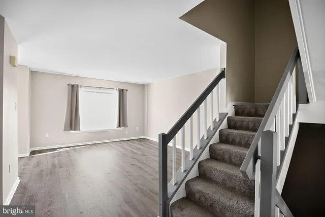 a view of an empty room with wooden floor and stairs