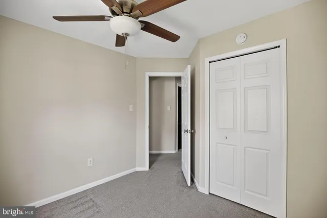 an empty room with closet and a chandelier fan