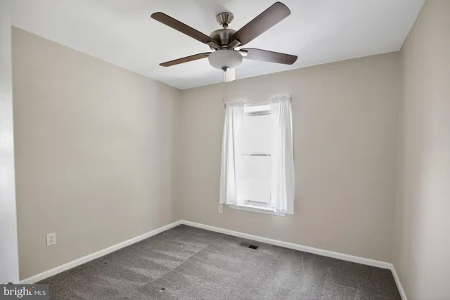 an empty room with a ceiling fan and a window