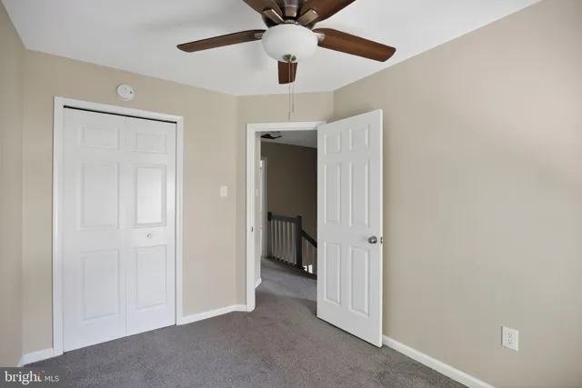 an empty room with a ceiling fan and hallway