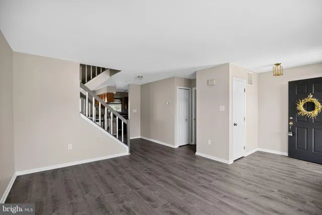 a hallway with wooden floor stairs and a living room