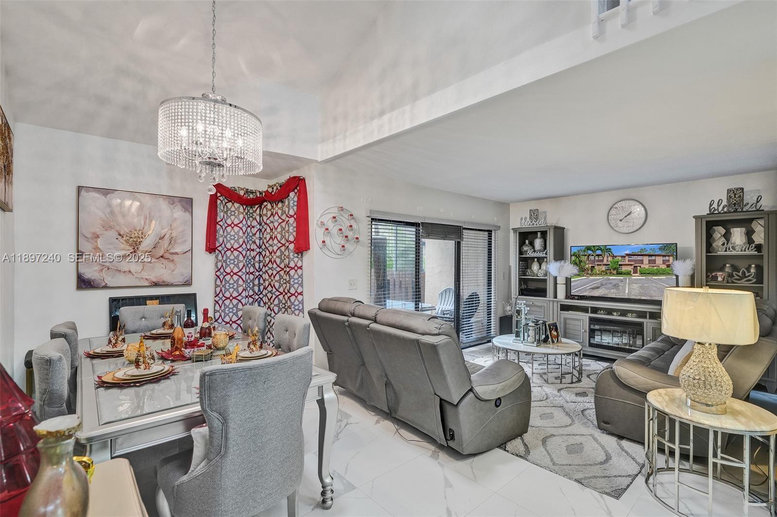 7780 Northwest 79th Avenue, Unit F6 Tamarac, FL 33321 - Photo 11 of 27 a living room with furniture a dining table and a chandelier