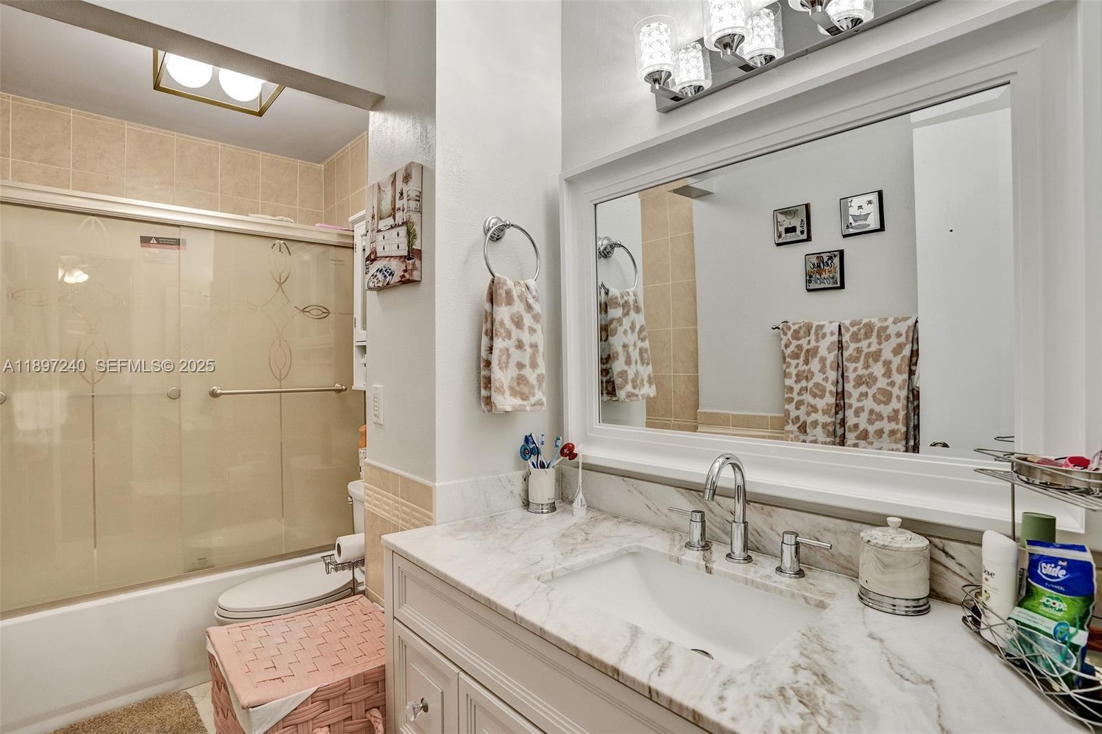 7780 Northwest 79th Avenue, Unit F6 Tamarac, FL 33321 - Photo 17 of 27 a bathroom with a granite countertop sink a mirror a bathtub and shower