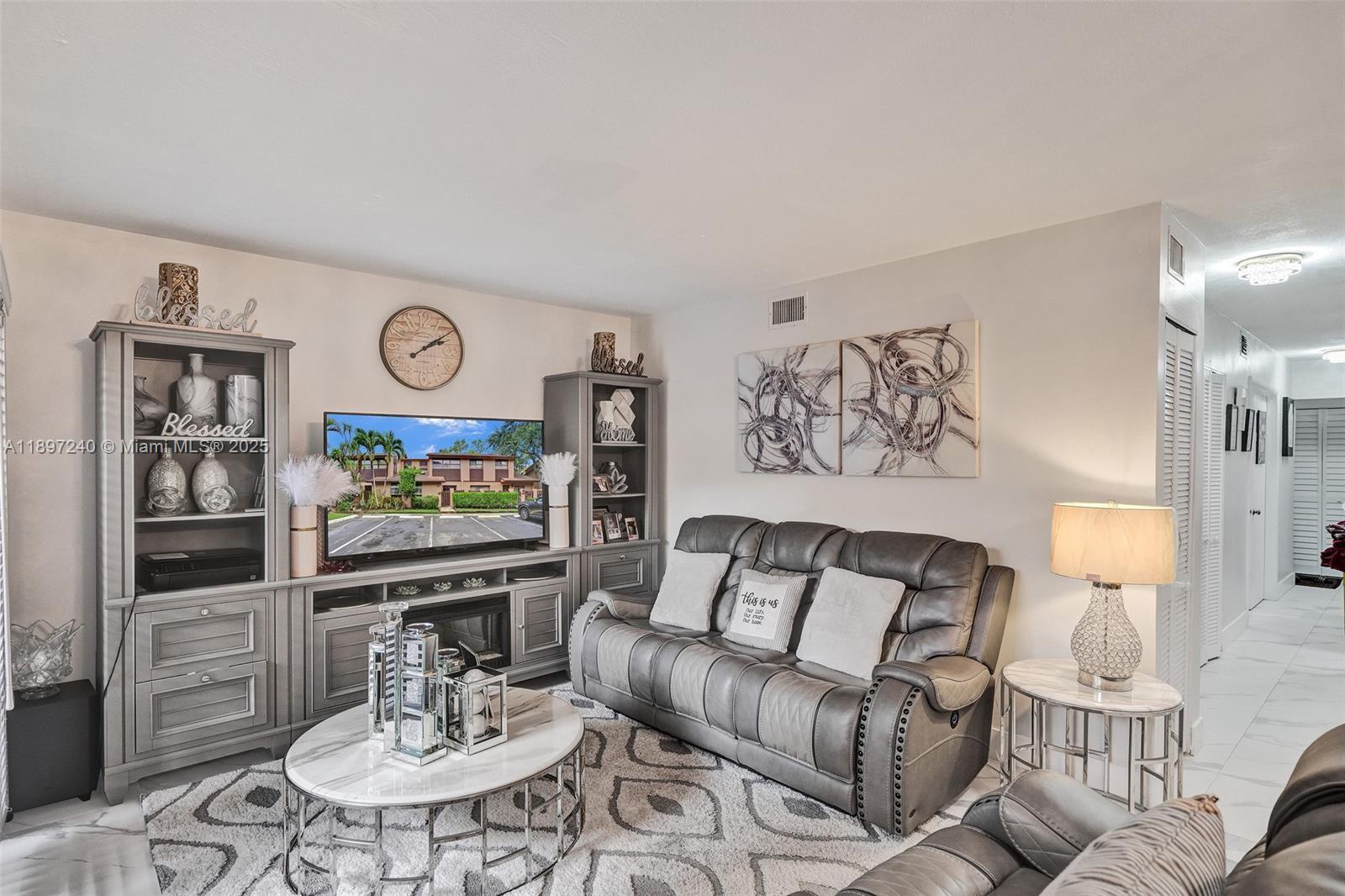 7780 Northwest 79th Avenue, Unit F6 Tamarac, FL 33321 - Photo 9 of 27 a living room with furniture and a flat screen tv