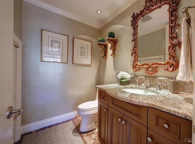 a bathroom with a granite countertop toilet sink and mirror