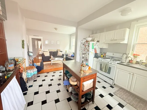 a large white kitchen with stainless steel appliances a stove a sink and a refrigerator