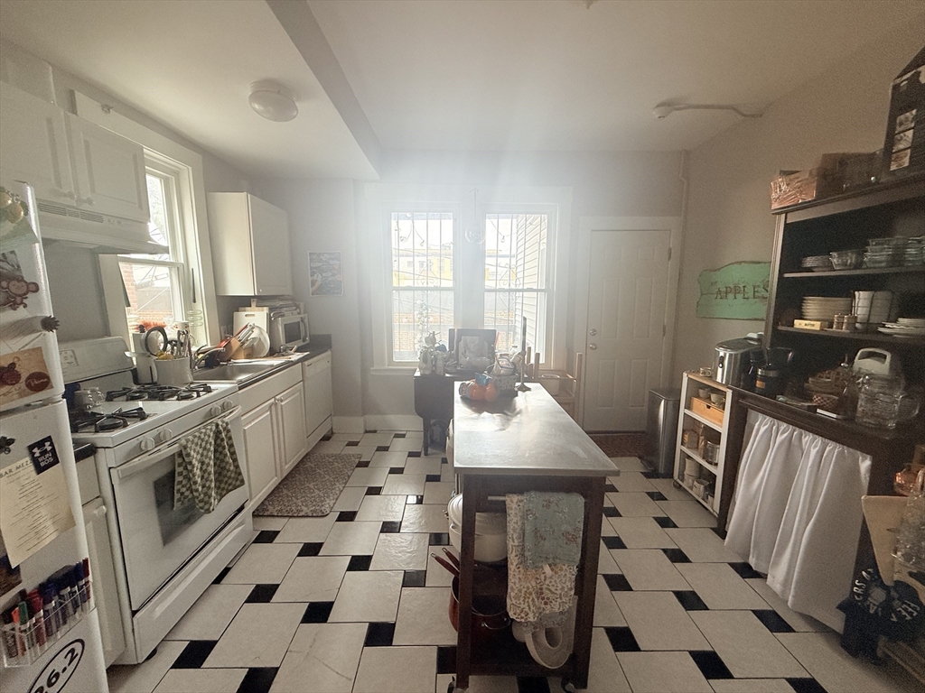 15 Chester Street, Unit 4 Boston, MA 02134 - Photo 17 of 20 a kitchen with stainless steel appliances a stove a sink a refrigerator wooden floor and a dining table