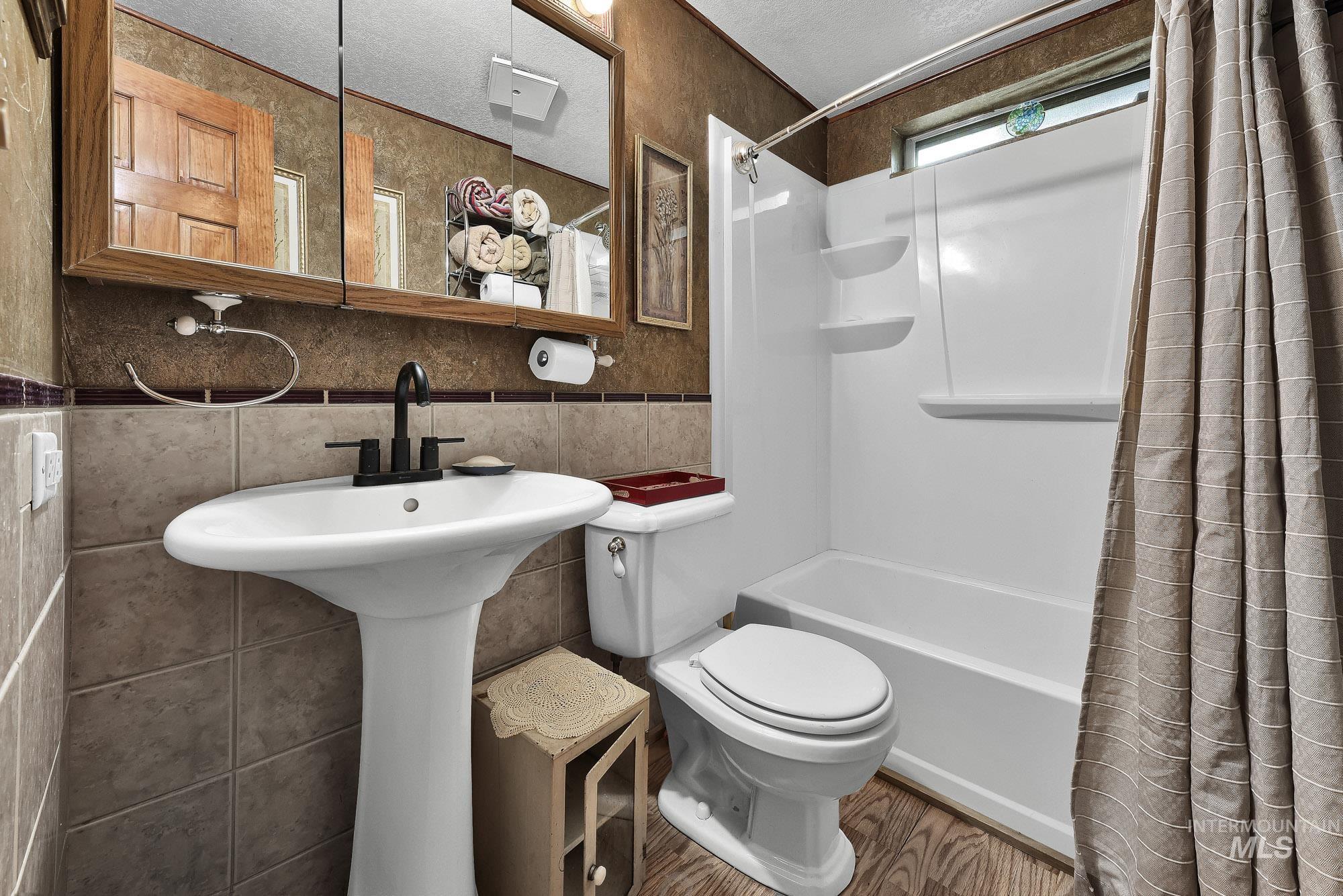 24900 Market Road Parma, ID 83660 - Photo 16 of 50 Bathroom featuring a pedestal sink with a matte black faucet, a large mirrored medicine cabinet, and a tiled accent wall