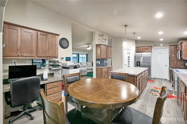 a dining room with stainless steel appliances kitchen island granite countertop a stove a sink a dining table and chairs with wooden floor