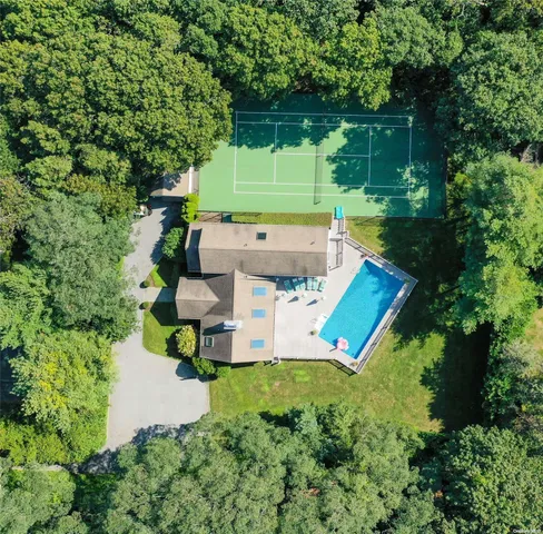 an aerial view of a house with a yard lake and trees all around